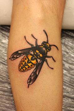 a black and yellow bee tattoo on the leg