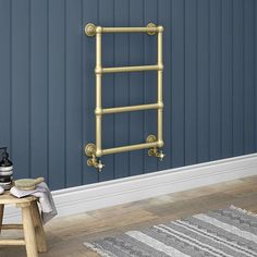 a bathroom with blue walls and a gold towel rack on the wall next to a stool