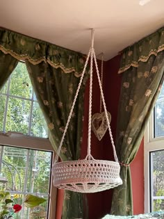 a chandelier hanging from the ceiling in front of two windows with curtains and green drapes