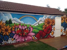 a colorful mural on the side of a building with sunflowers and flowers painted on it