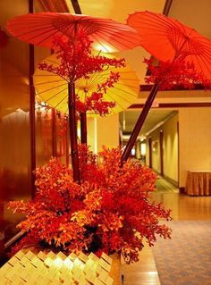 three red umbrellas sitting on top of a wooden table next to flowers and candles