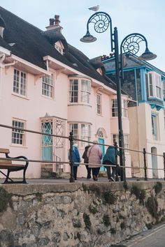 three people walking up the steps to a pink house