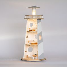 a white lighthouse shaped lamp on top of a wooden shelf next to a gray wall