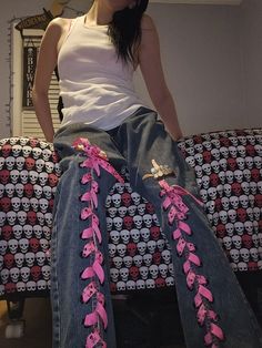 a woman sitting on top of a couch wearing jeans with skulls and flowers painted on them