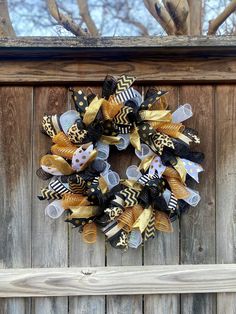 a yellow and black wreath hanging on the side of a wooden fence