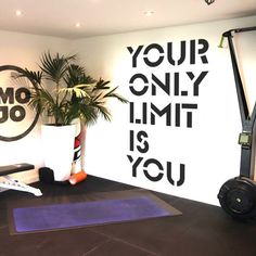 there is a gym room with exercise mats on the floor and a wall that says your only limit is you