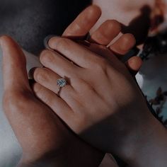 two hands holding each other with a diamond ring