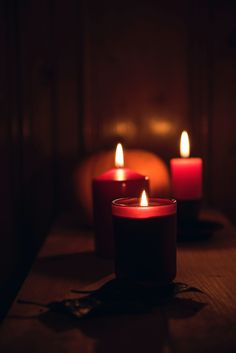 three lit candles sitting on top of a wooden table