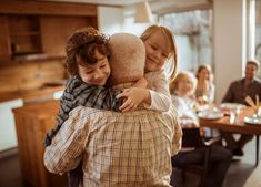 two children hugging each other in the middle of a room with people sitting at tables