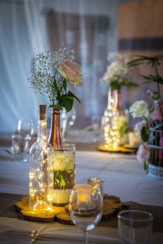 the table is set with wine bottles, candles and flowers