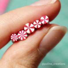 three red and white candy canes sitting on top of someone's finger