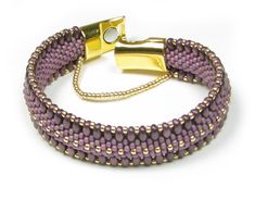 a purple and gold beaded bracelet with two clasps on the end is shown