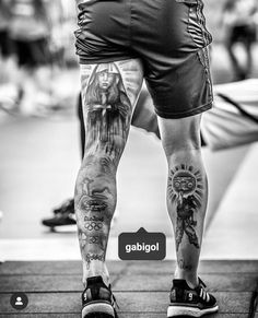 a man with tattoos on his legs standing in front of a skateboarder's feet