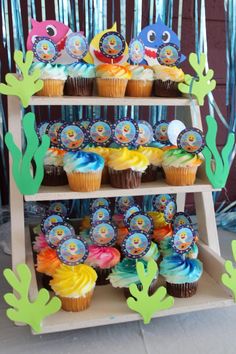 cupcakes are displayed on three tiered shelves in the shape of sea animals