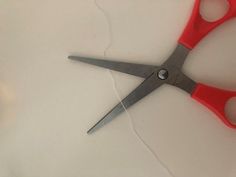 a pair of red scissors sitting on top of a white table next to each other