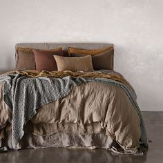 a bed with pillows and blankets on it in a room that has concrete flooring