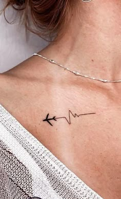 a woman's chest with an arrow tattoo on the left side of her neck