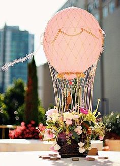 a pink hot air balloon sitting on top of a table next to flowers and candles