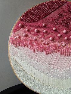 a close up of a piece of art with beads and thread on the bottom of it