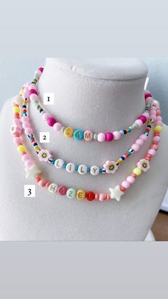 three different necklaces with letters and numbers on each beaded stranding, one is multicolored