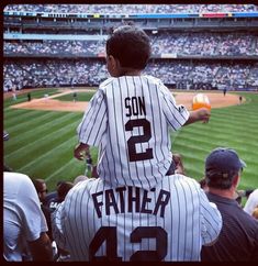 a baseball player is sitting on his father's shoulders at a game in the stadium