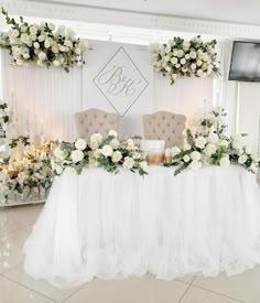 the table is set up with white flowers and greenery for an elegant wedding reception