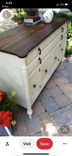 an old dresser is painted white and has black knobs on the drawers, along with red flowers