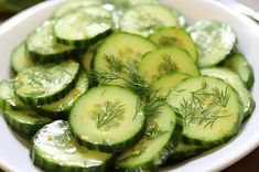 sliced cucumbers in a white bowl with dill