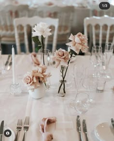 the table is set with silverware and pink flowers in vases on each side