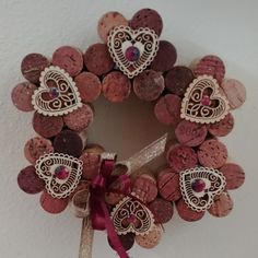 a wreath made out of wine corks with hearts on the front and sides, tied to a wall