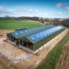 an aerial view of a building with solar panels on the roof and grass in the foreground