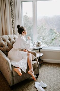 a woman sitting in a chair with her feet up on the floor next to a window