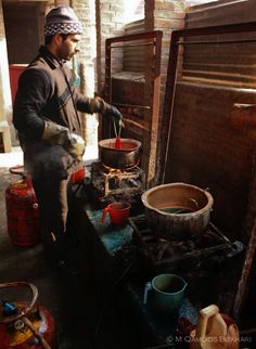 a man is cooking food on an old stove in the kitchen area with other pots and pans