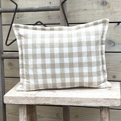 a brown and white checkered pillow sitting on top of a wooden bench next to a wall