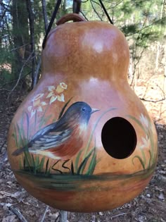 a birdhouse painted with flowers and birds on it's side in the woods