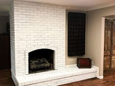 an empty living room with a white brick fireplace