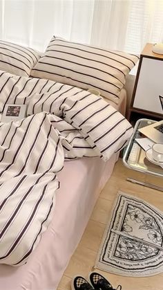 a bed with white and black striped comforter next to a pair of shoes on the floor