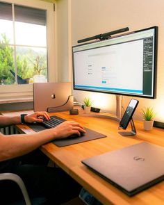 a man sitting at a desk with a laptop and a computer monitor on top of it