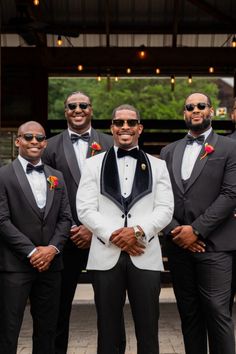 a group of men standing next to each other wearing suits and ties with sunglasses on