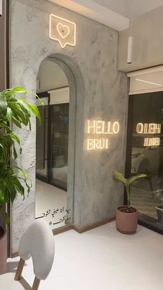 the entrance to hello bru is lit up with neon lights and a potted plant