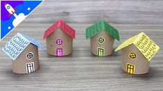 three little houses made out of toilet paper on top of a wooden table with an airplane flying over them