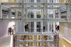 people are standing in the middle of a building with glass walls and metal railings