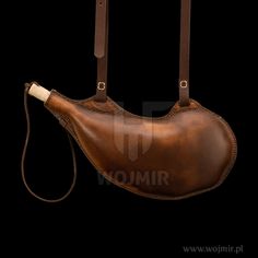 a brown leather bag with straps hanging from it's side on a black background