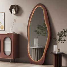 an oval shaped mirror in the corner of a room next to a table with a vase on it