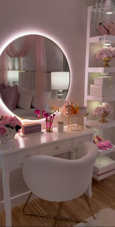 a white desk topped with a mirror next to a chair and table covered in pink flowers