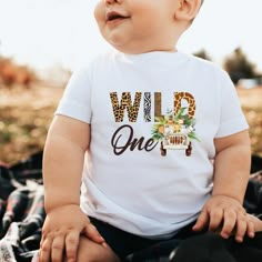 a baby wearing a white shirt with the words wild one printed on it's chest