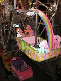 a carnival ride with many ponies and rainbows on the rides, including one pink car