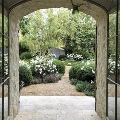 an archway leading into a garden with white flowers