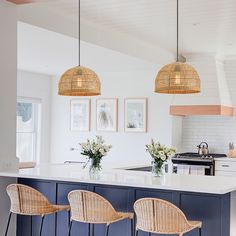 three wicker chairs sit at an island in the middle of a kitchen with white counter tops and blue cabinets