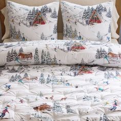 a bed with white comforter and pillows covered in ski themed snow scene designs on it